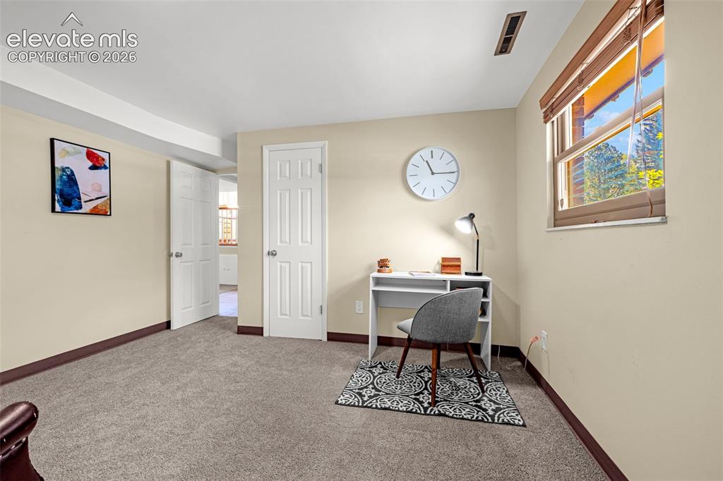 Image 29 of 38: Carpeted room featuring a single window with blinds, beige walls, and white