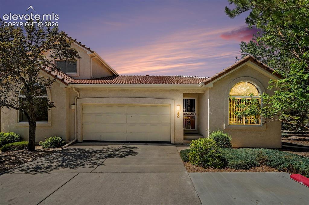 Caption: Stucco exterior with a tile roof, an integrated garage, a security screen door, and an arched window