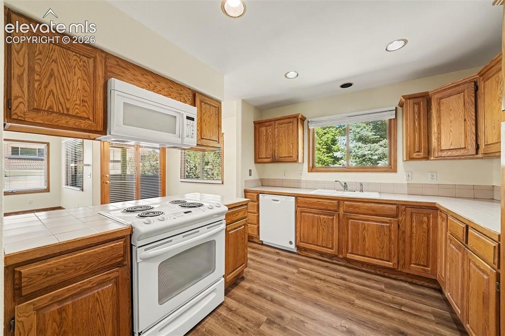 Image 10 of 47: Kitchen featuring wood-finish cabinetry, white appliances, recessed lightin