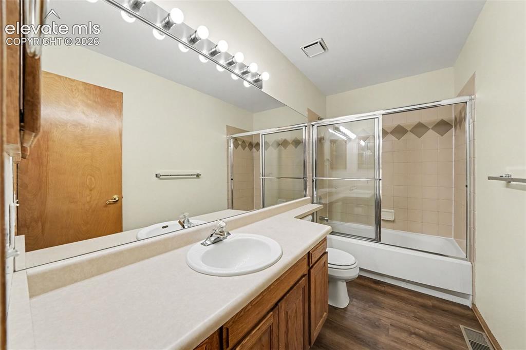 Image 18 of 47: LVP flooring, full vanity with integrated sink, large wall-mounted mirror, 