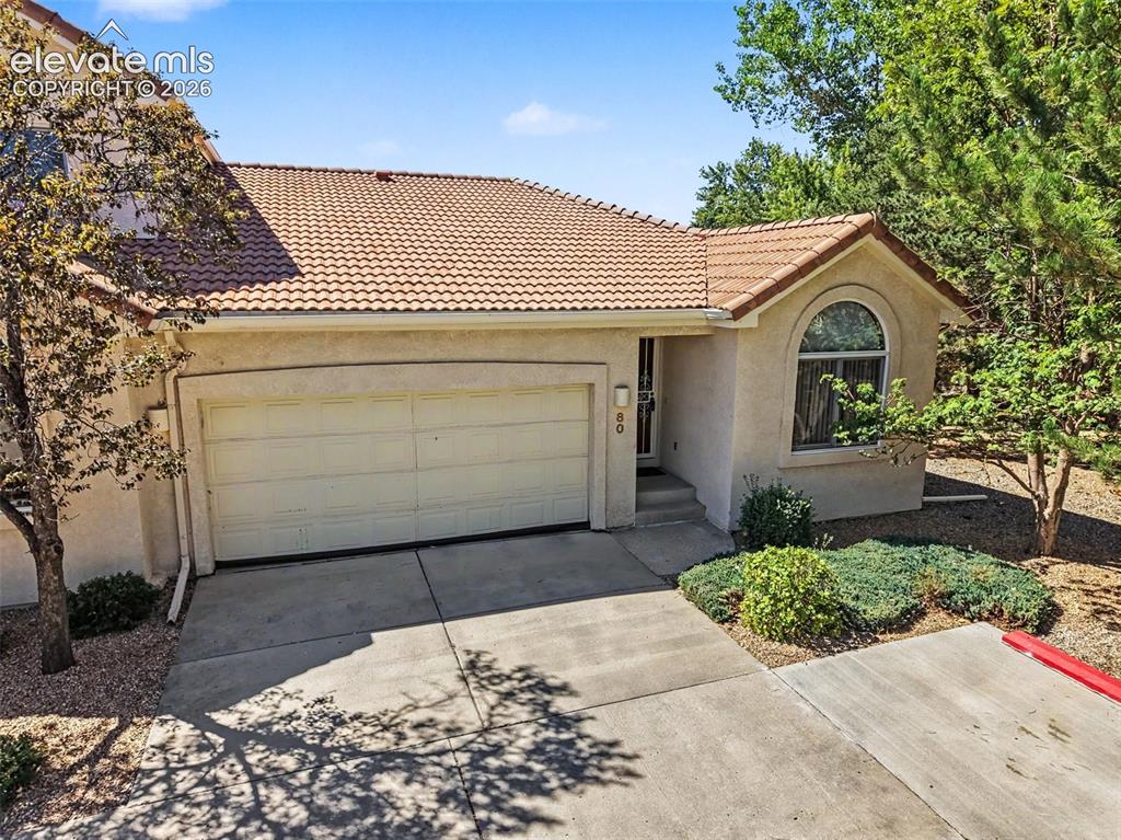 Image 2 of 47: Stucco exterior with a tile roof, an arched transom window, an attached gar