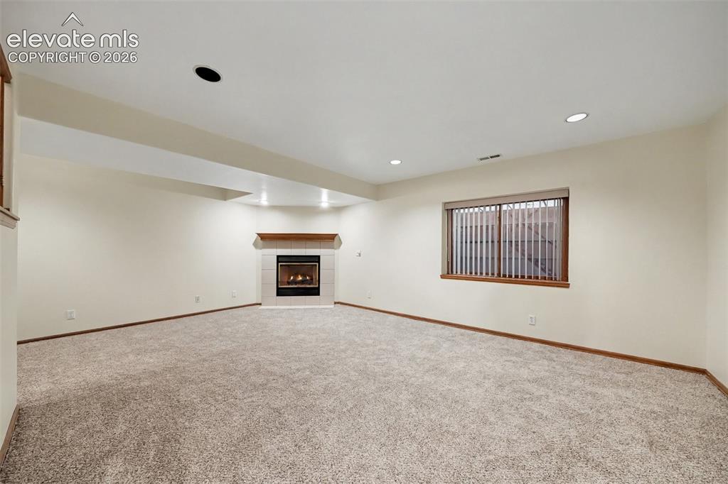 Image 30 of 47: Expansive carpeted room featuring a built-in fireplace with a tile surround
