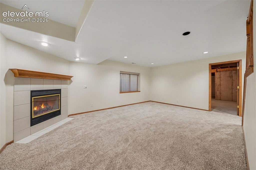 Image 32 of 47: Carpeted room featuring a tile-surround fireplace with a wood mantel, reces