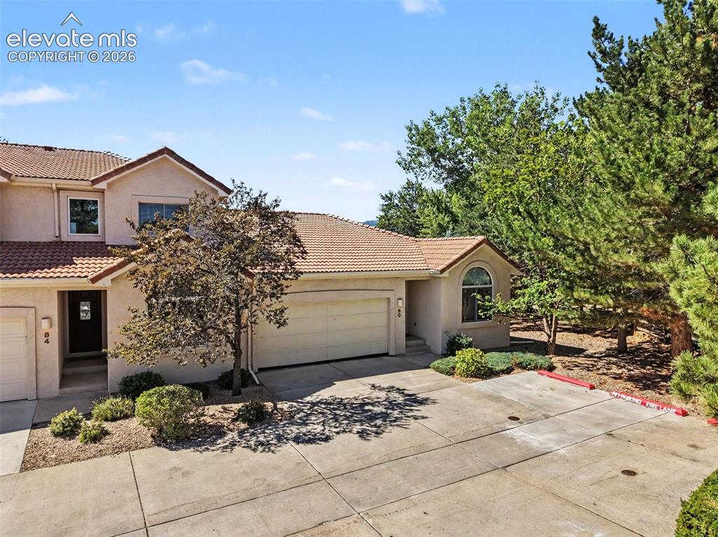 Image 46 of 47: Stucco exterior with a tile roof, an arched window, and an attached garage