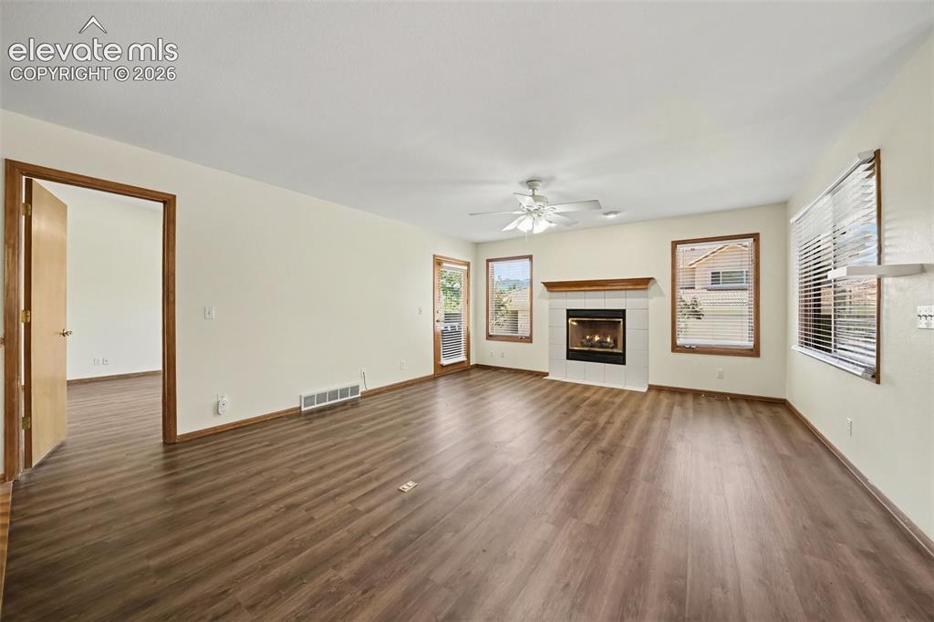 Image 6 of 47: New LVP flooring throughout, white-tiled fireplace with wood mantel, ceilin