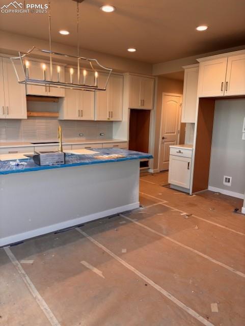 Image 4 of 14: Kitchen with decorative backsplash, white cabinetry, hanging light fixtures
