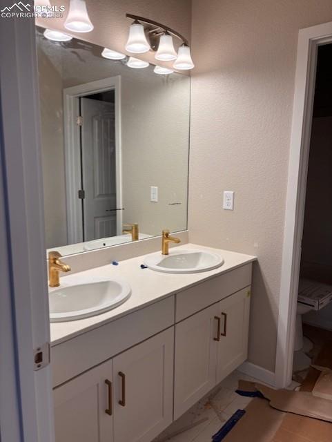 Image 6 of 14: Bathroom with double vanity, a textured wall, and light tile patterned floo