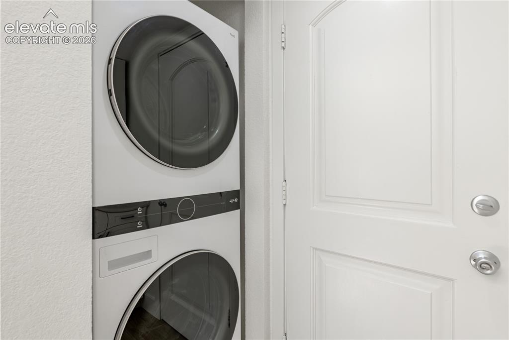 Image 11 of 28: Stacked front-loading washer and dryer unit with a sleek white finish and m