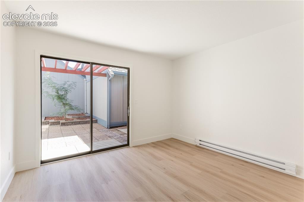 Image 13 of 28: Interior space featuring wood-finish flooring, sliding glass door, and a pa