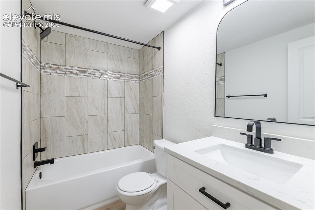 Image 14 of 28: Bathroom featuring a white vanity with a quartz countertop, arched wall mir