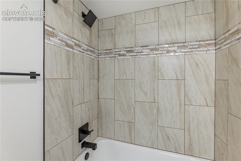 Image 15 of 28: Bathtub surround featuring large-format neutral-tone wall tile, horizontal 