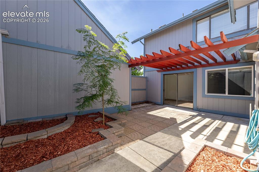 Image 16 of 28: Private patio featuring a stamped concrete surface, integrated wood pergola