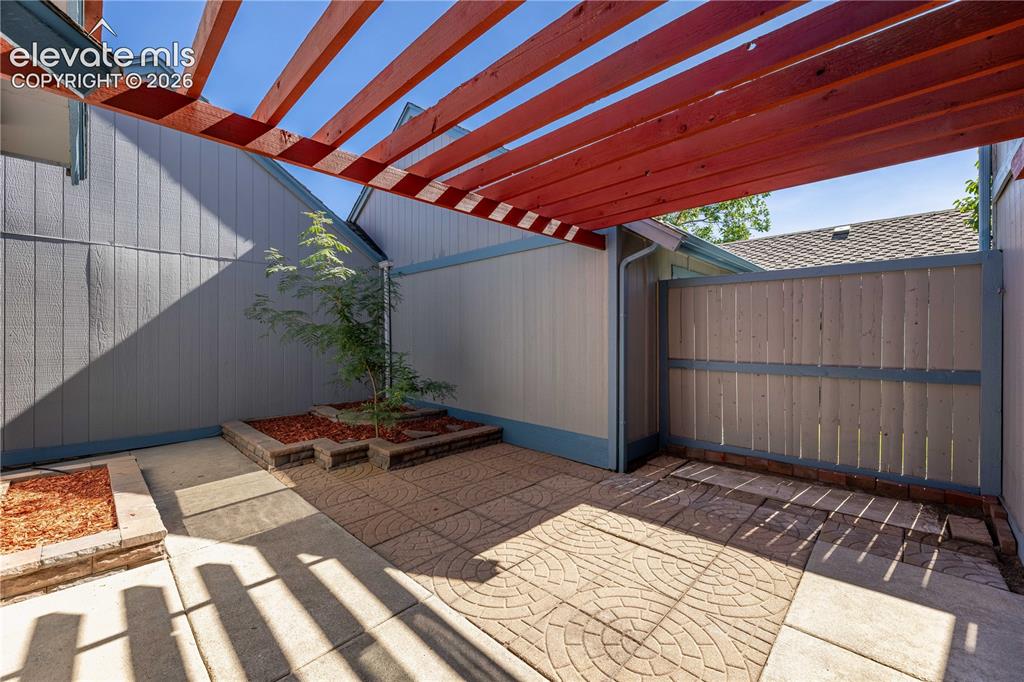 Image 17 of 28: Private courtyard featuring a wood-beam pergola, patterned concrete pavers,