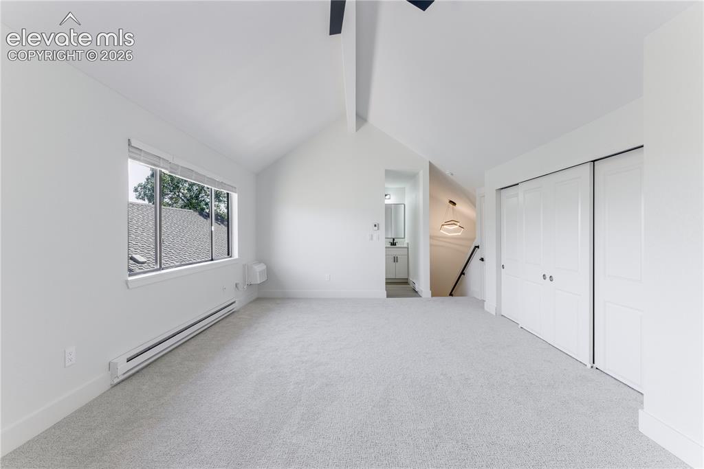 Image 21 of 28: Vaulted ceiling featuring a central exposed beam, neutral wall-to-wall carp