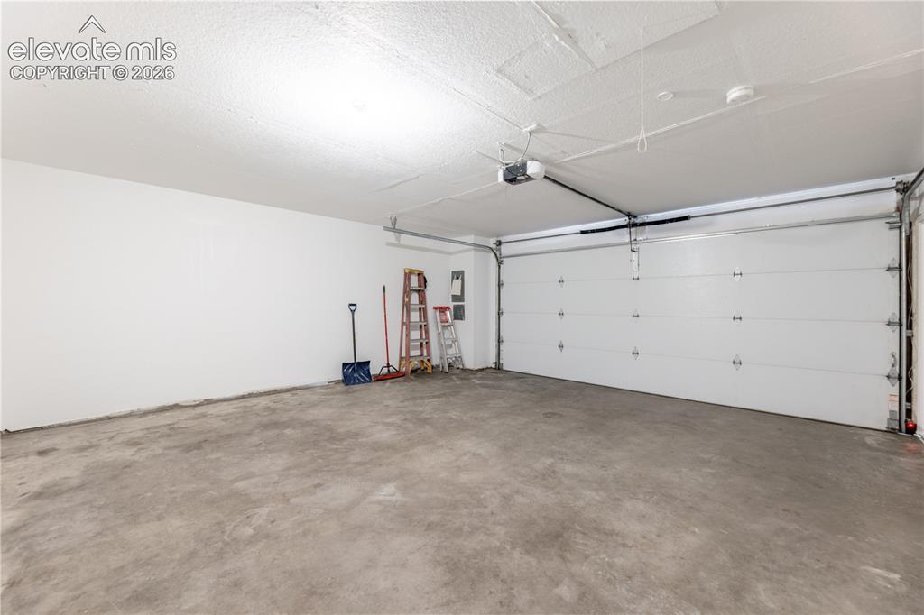 Image 24 of 28: Spacious two-car garage featuring a concrete floor, high ceilings, and an a