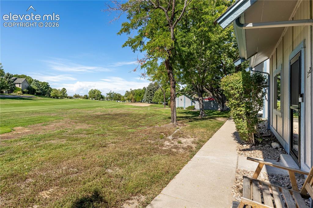 Image 26 of 28: Exterior property grounds featuring a concrete walkway, mature trees, and o