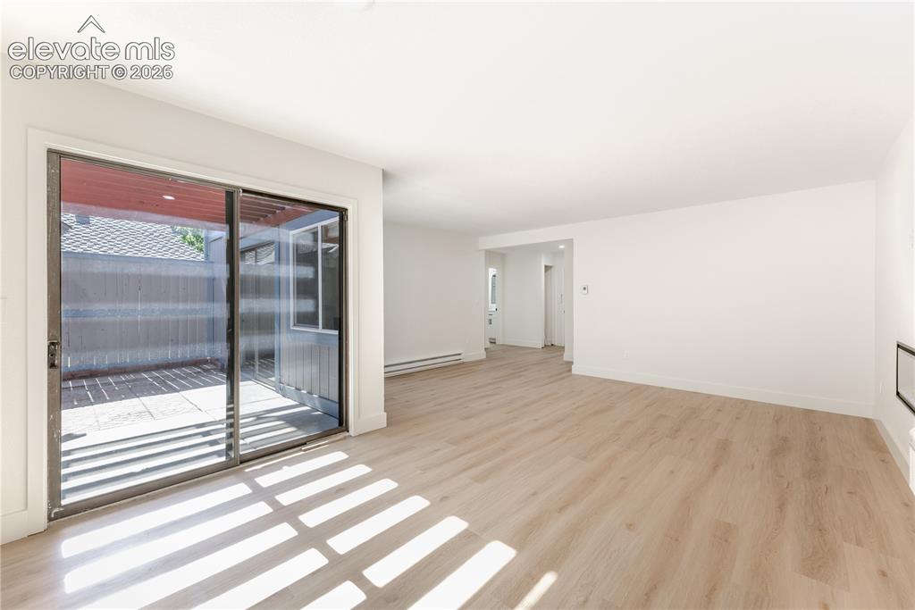 Image 6 of 28: Living area featuring wood-finish flooring, smooth ceilings, and sliding gl