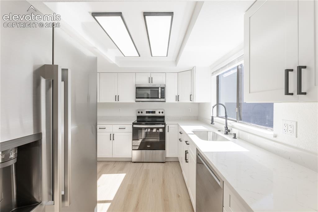 Image 7 of 28: Kitchen featuring shaker-style white cabinetry, quartz countertops, stainle