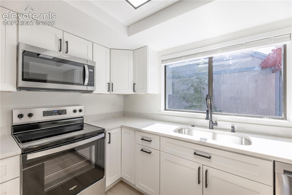 Image 8 of 28: Kitchen featuring white Shaker-style cabinetry, stainless steel appliances,