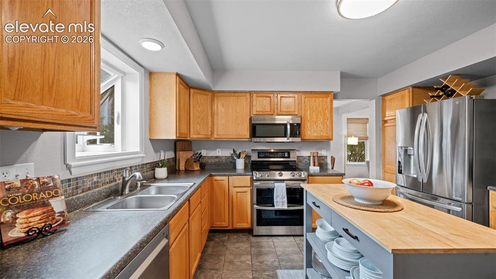 Image 11 of 30: Kitchen featuring light wood cabinetry, stainless steel appliances, a tile