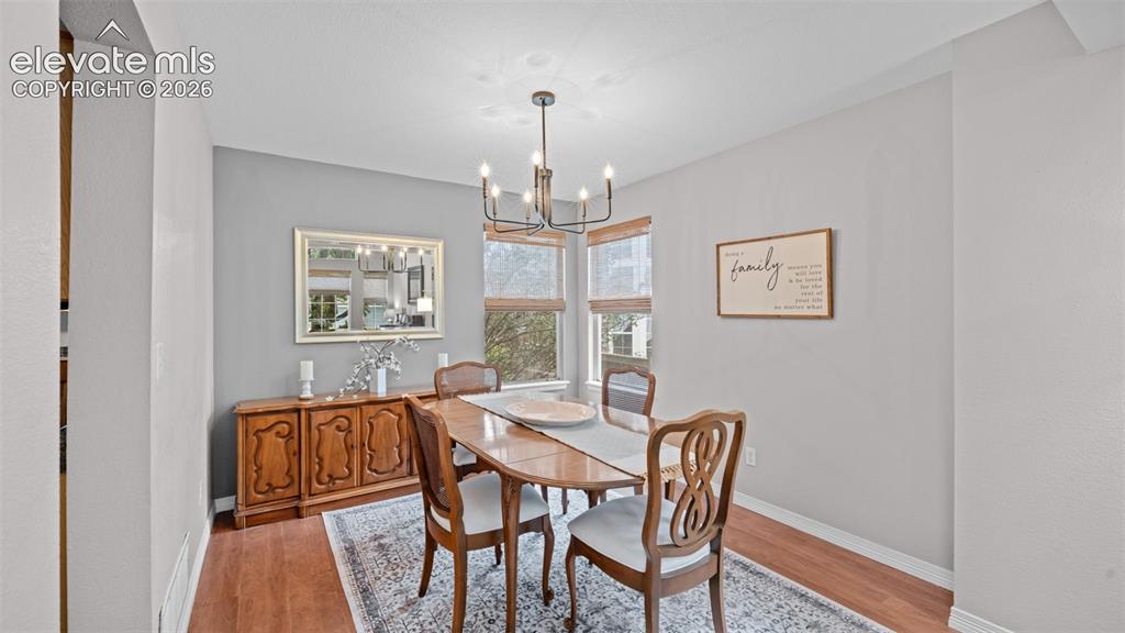Image 14 of 30: Dining area with wood-finish flooring, a contemporary black chandelier, and