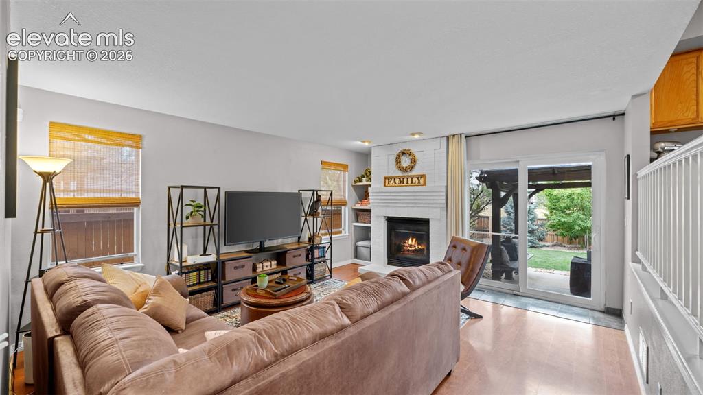 Image 15 of 30: Living area featuring wood-finish flooring and a white brick fireplace