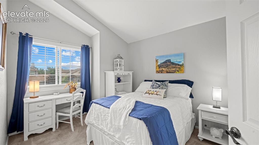 Image 18 of 30: Bedroom featuring a vaulted ceiling and window with horizontal blinds