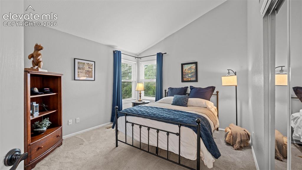 Image 19 of 30: Bedroom featuring a vaulted ceiling, bay windows, and mirrored closet doors