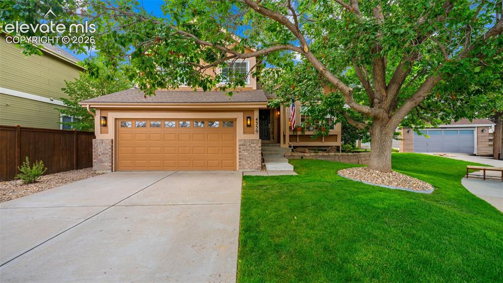 Image 2 of 30: Two-story residence featuring a two-car garage with panel detailing, stone