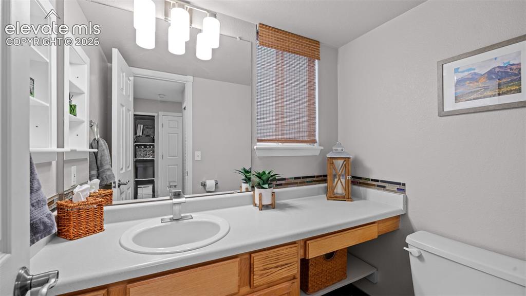 Image 20 of 30: Bathroom featuring a single vanity with an integrated sink, wood cabinetry,