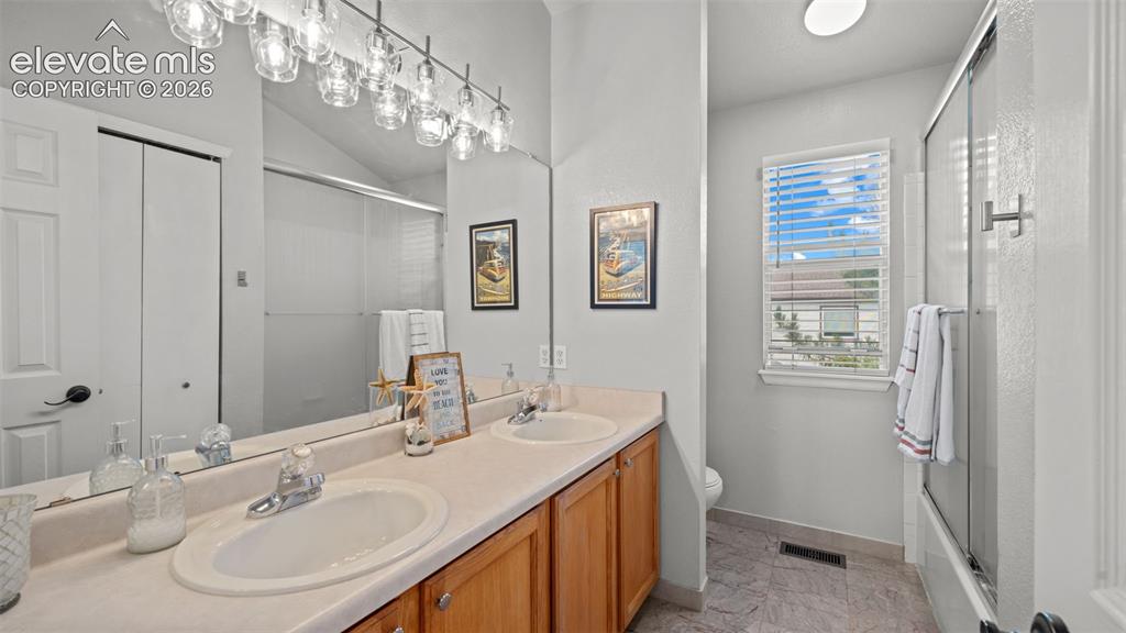 Image 21 of 30: Dual vanity with light wood cabinetry, a large wall-mounted mirror, and ove
