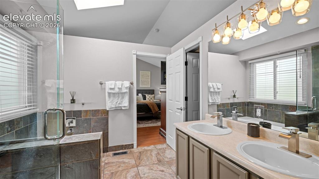 Image 25 of 30: Bathroom featuring a dual vanity with undermount sinks, a glass-enclosed sh
