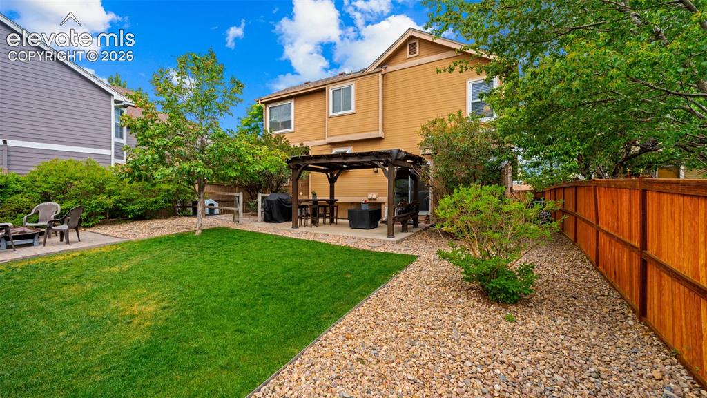 Image 26 of 30: Private backyard featuring a central lawn, a pergola-covered patio, and a p