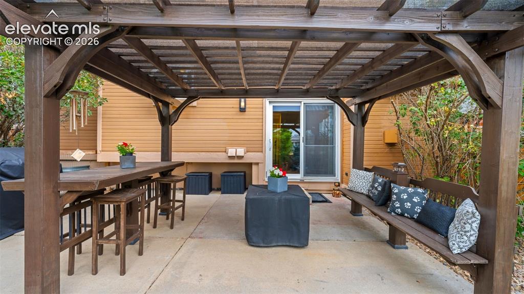 Image 29 of 30: Expansive concrete patio featuring a sturdy wooden pergola, sliding glass d