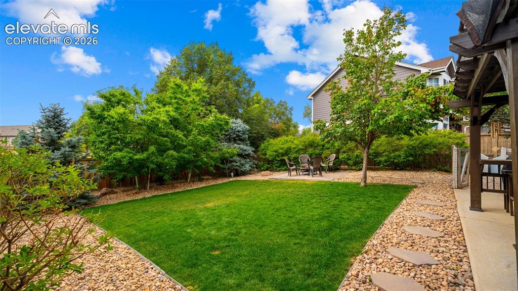 Image 30 of 30: Expansive green lawn framed by decorative rock landscaping