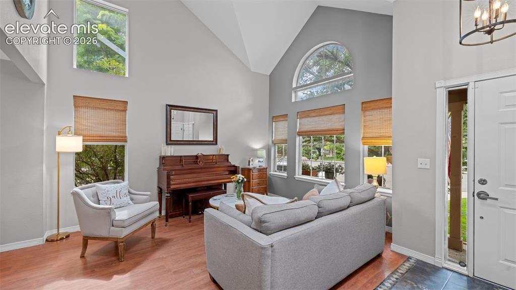 Image 6 of 30: Vaulted ceiling living area featuring wood-finish flooring