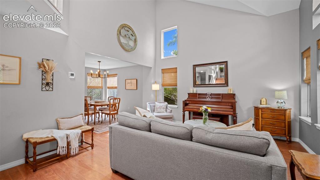Image 8 of 30: Spacious living area featuring high vaulted ceilings and wood-finish floori