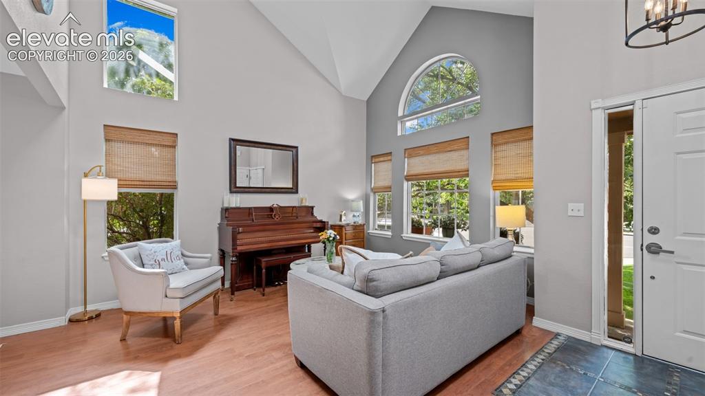 Image 9 of 30: Vaulted ceiling living room featuring wood-finish flooring and multiple win