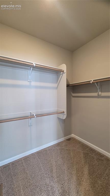 Image 16 of 36: Primary walk-in closet with wood shelving and rods!