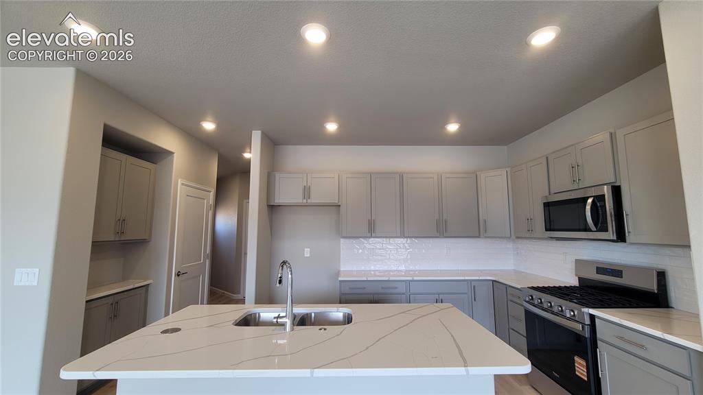 Image 7 of 36: Kitchen with Quartz countertops, pantry, large island, and stainless steel