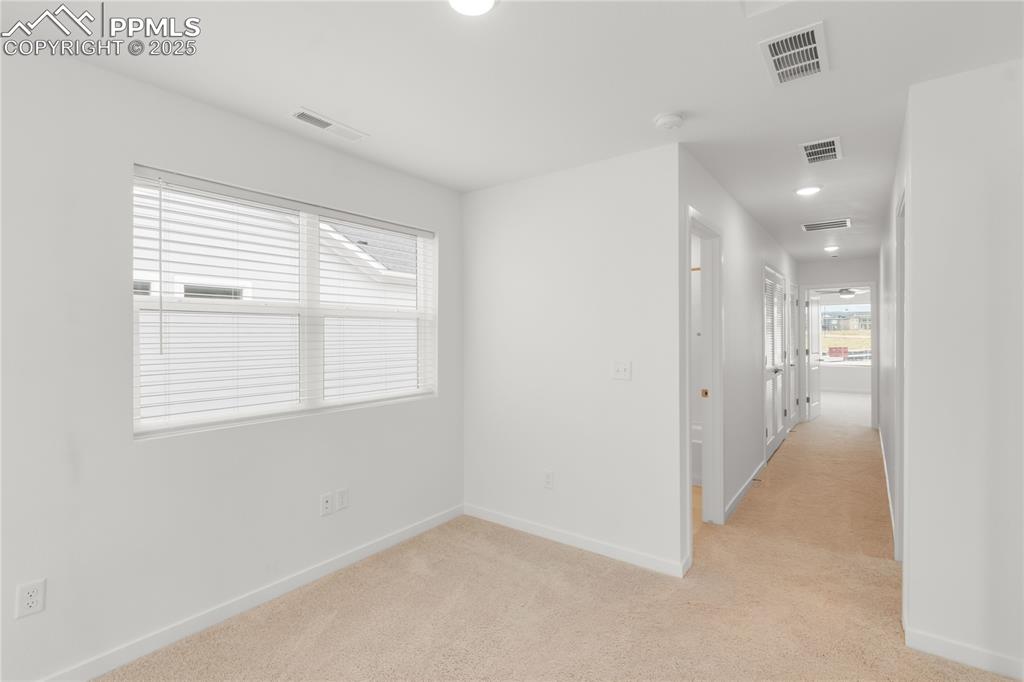 Image 18 of 39: Hallway with light carpet and recessed lighting