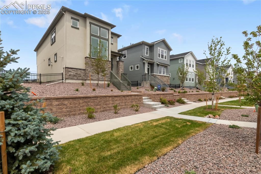 Image 2 of 39: View of front facade featuring stone siding, a residential view, and stucco
