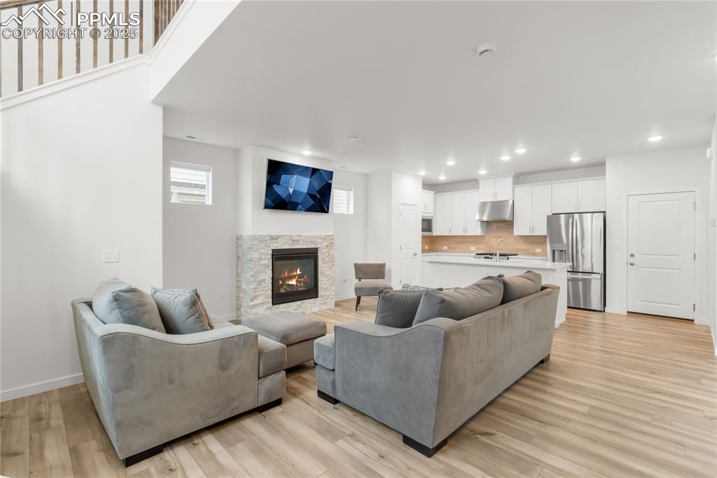 Image 21 of 39: Living area featuring a fireplace, light wood-style floors, and recessed li