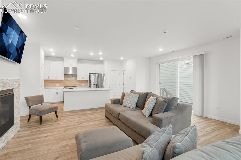 Image 22 of 39: Living room featuring a glass covered fireplace, light wood-style flooring,