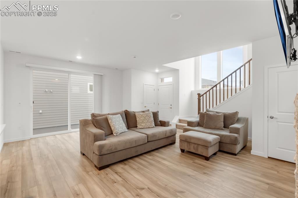 Image 25 of 39: Living room featuring light wood-style floors, stairway, and recessed light