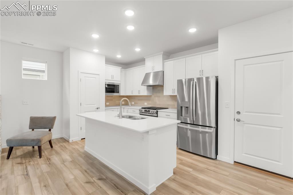 Image 26 of 39: Kitchen with stainless steel appliances, under cabinet range hood, decorati