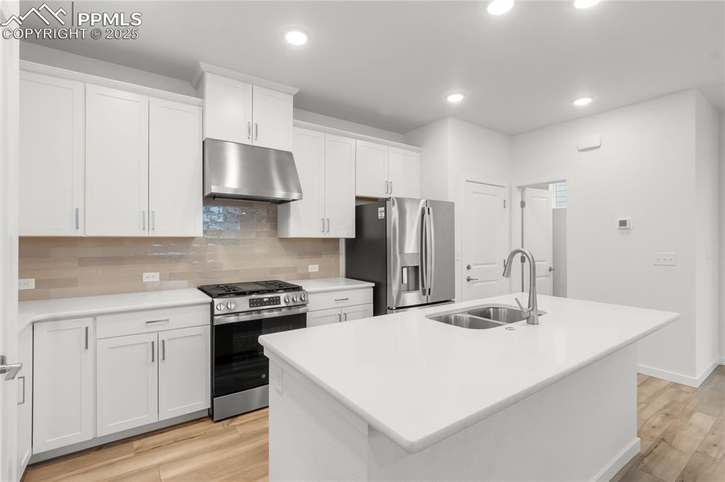 Image 27 of 39: Kitchen featuring stainless steel appliances, under cabinet range hood, tas