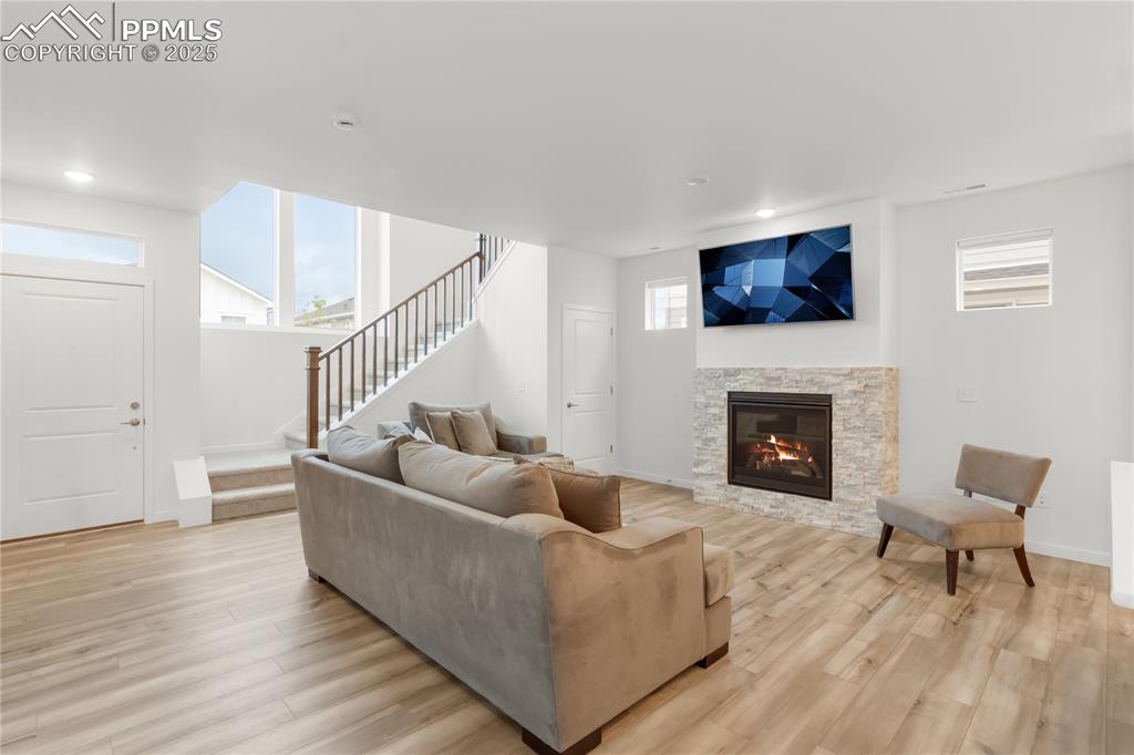 Image 28 of 39: Living area featuring stairway, a fireplace, light wood-style floors, and r