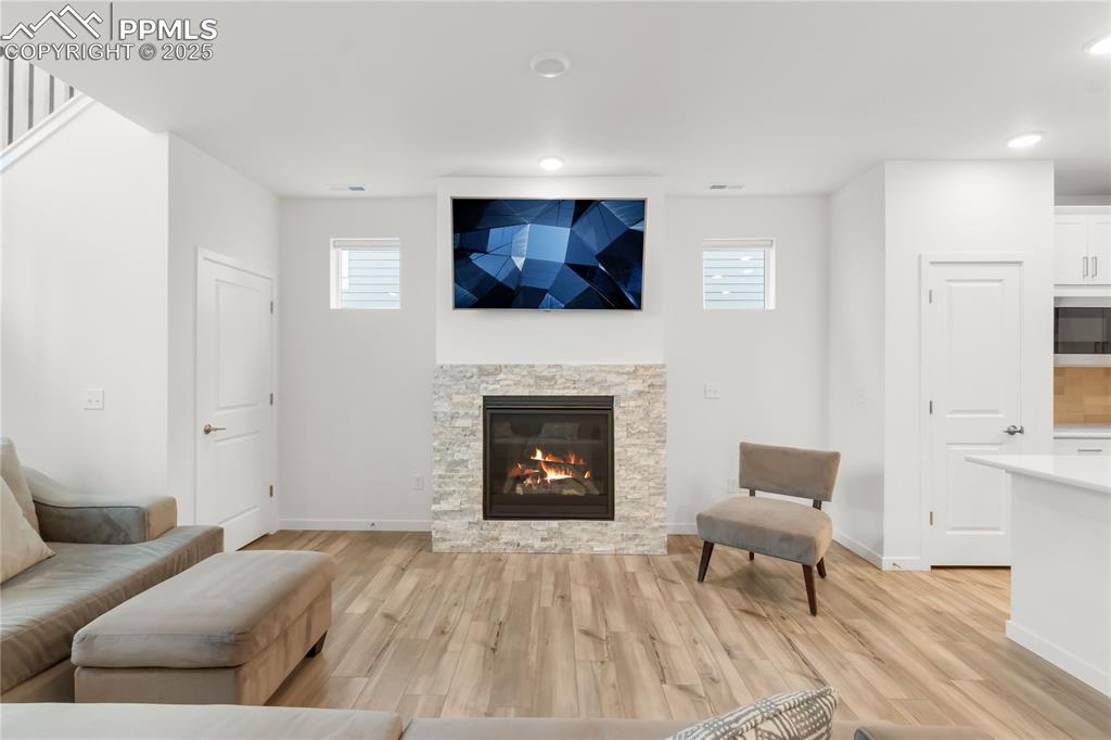 Image 29 of 39: Living area with light wood-style floors, a fireplace, and recessed lightin
