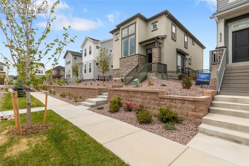 Image 3 of 39: View of front of house with a residential view, stone siding, stucco siding